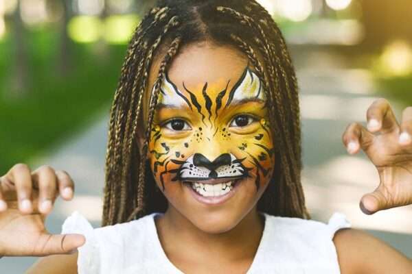 Adorable african-american girl with creative face painting roaring