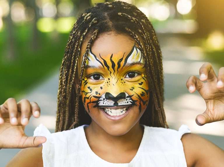 Adorable african-american girl with creative face painting roaring